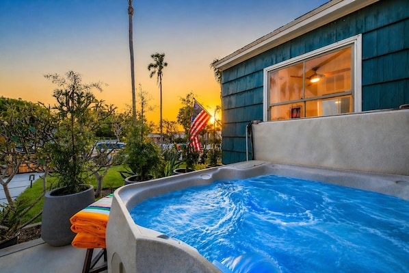 A hot tub with a view of a sunset, a flag, and a house with a window. - Walk To The Village, Beach, Restaurants W/Jacuzzi! (San Diego)