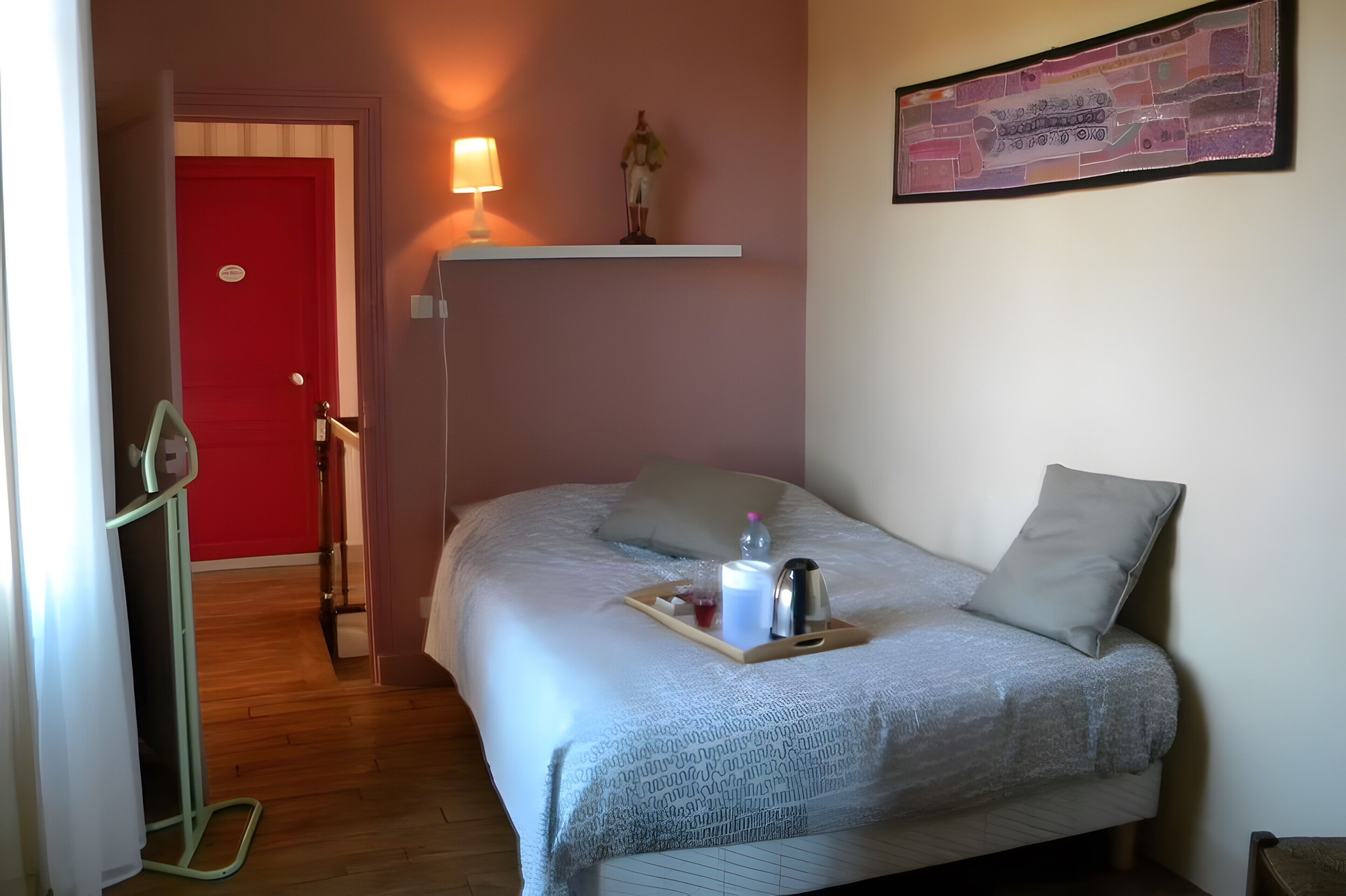 Ein ordentlich eingerichtetes Schlafzimmer mit Bett, Nachttisch, Lampe und einem Wandbild.