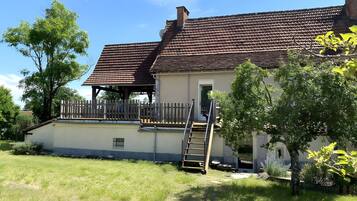 A house with a tiled roof, a wooden deck, and a ladder leading to a door.