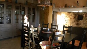 Een eetruimte met een tafel, stoelen, een kast met glazen deuren en een hanglamp.