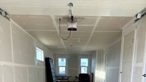 Un vaste espace intérieur inachevé, doté de planchers en béton, de murs blancs et d’un projecteur fixé au plafond.