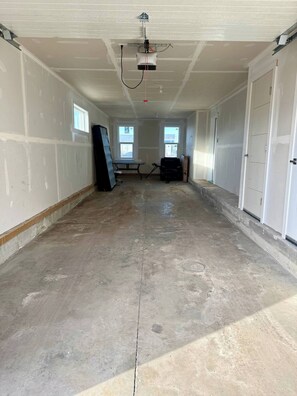 Ein großzügiger, noch unvollendeter Innenraum mit Betonböden, weißen Wänden und einem an der Decke befestigten Projektor.
