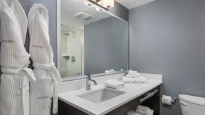 Un bagno moderno con uno specchio grande, un lavandino bianco e un water.