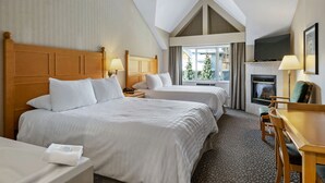 Una camera d'albergo con due letti, una scrivania, un camino e una televisione.