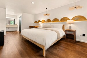 Un dormitorio moderno con una cama de madera, lámparas de noche y un ventilador de techo.