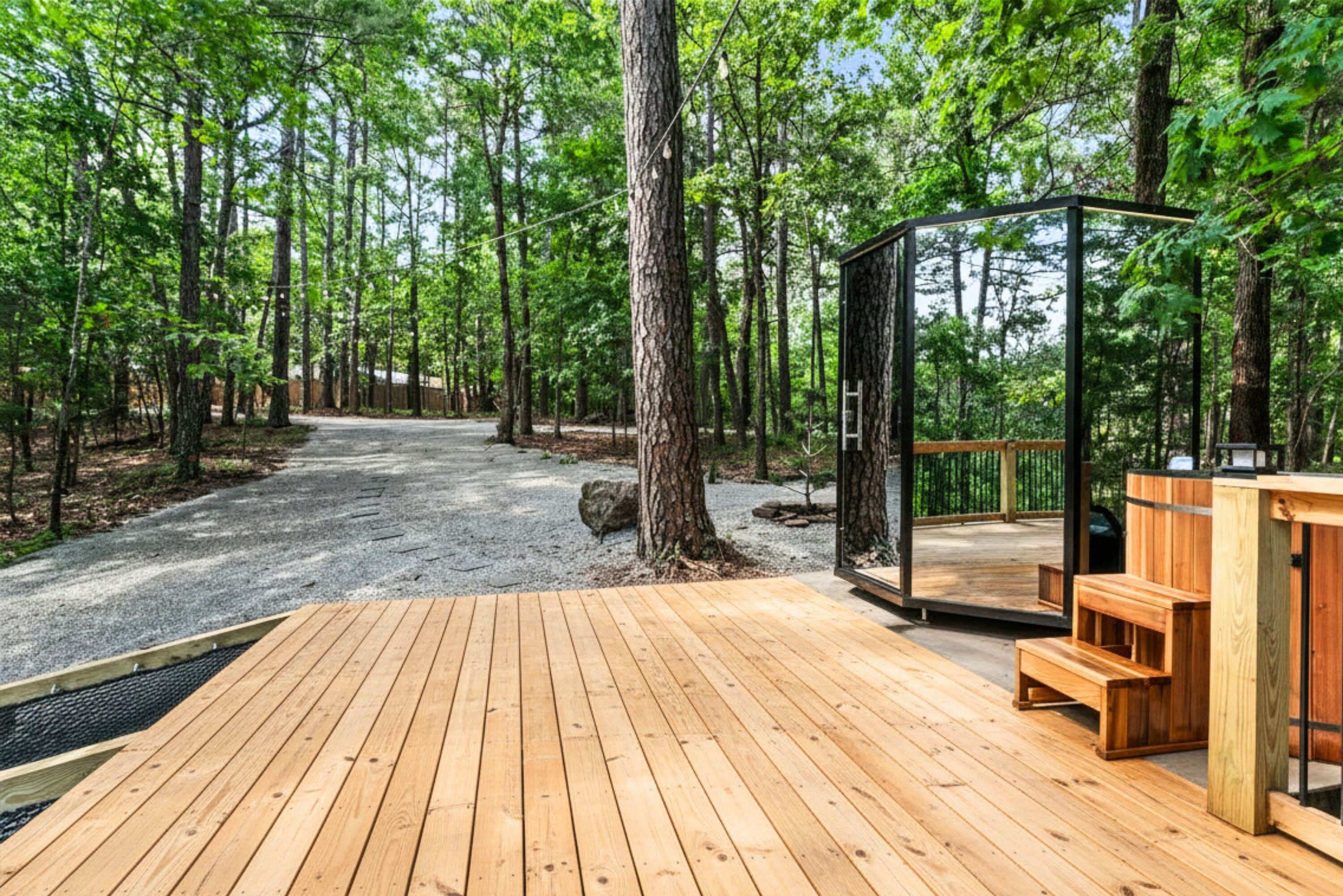A wooden deck with a glass enclosure, surrounded by a forest.