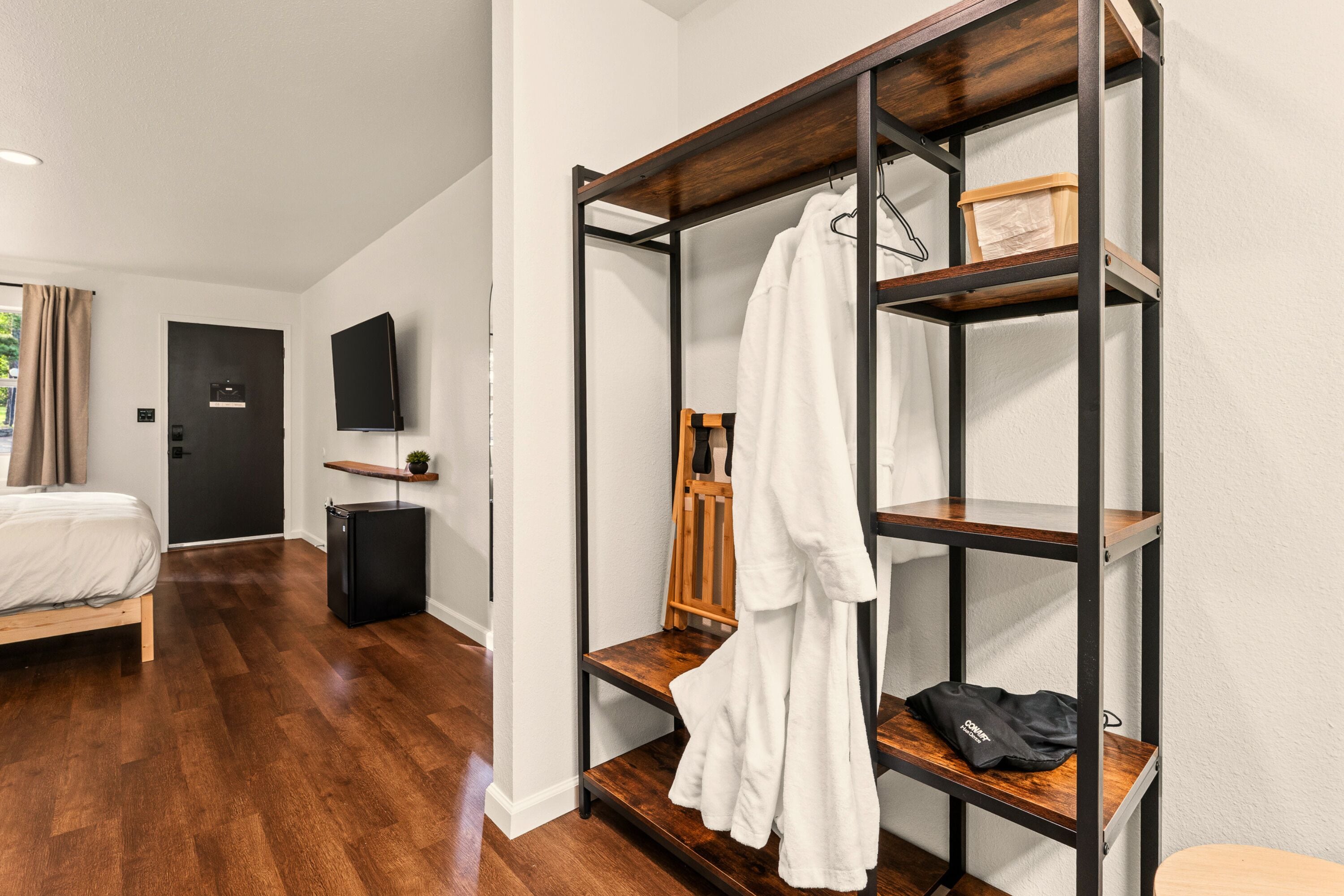 Una habitación de hotel con una cama, un armario, un televisor y un pequeño escritorio con una silla.