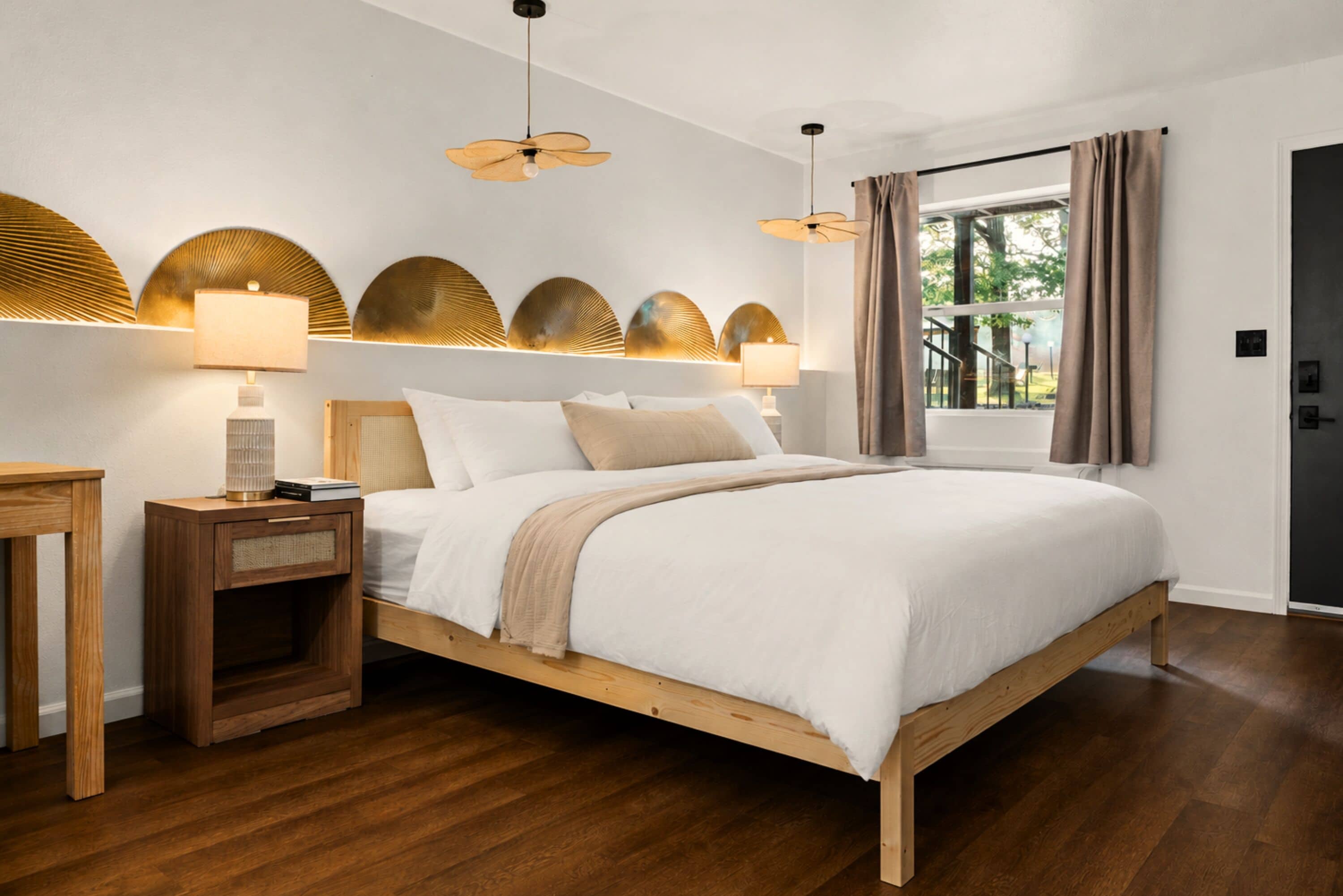 A bedroom with a wooden bed, bedside lamps, a nightstand, and a window with curtains.