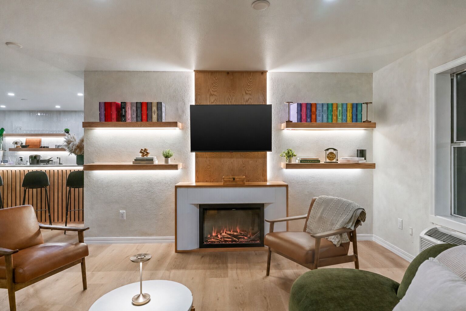 Un salon moderne doté d’une cheminée, de bibliothèques, d’un téléviseur à écran plat et de sièges confortables.