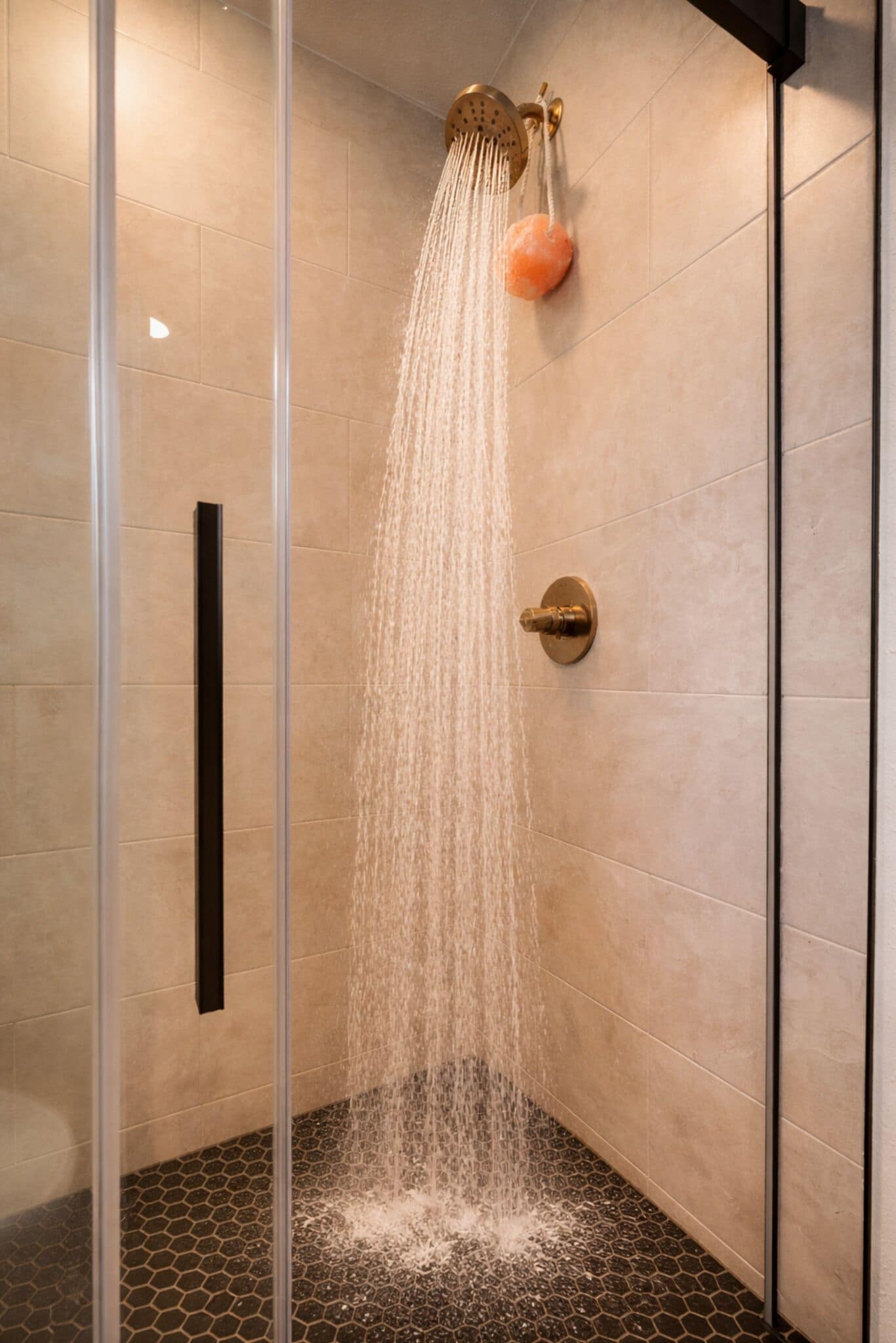 A shower with a rain showerhead, a glass enclosure, and a tiled floor.
