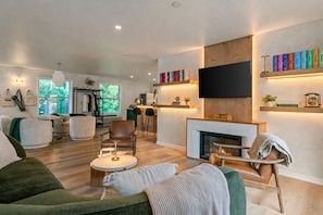 Una sala de estar moderna con chimenea, un televisor de pantalla plana montado arriba y una estantería con libros.