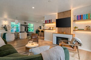 Uma sala de estar moderna com lareira, uma televisão de tela plana montada acima dela e uma estante com livros.