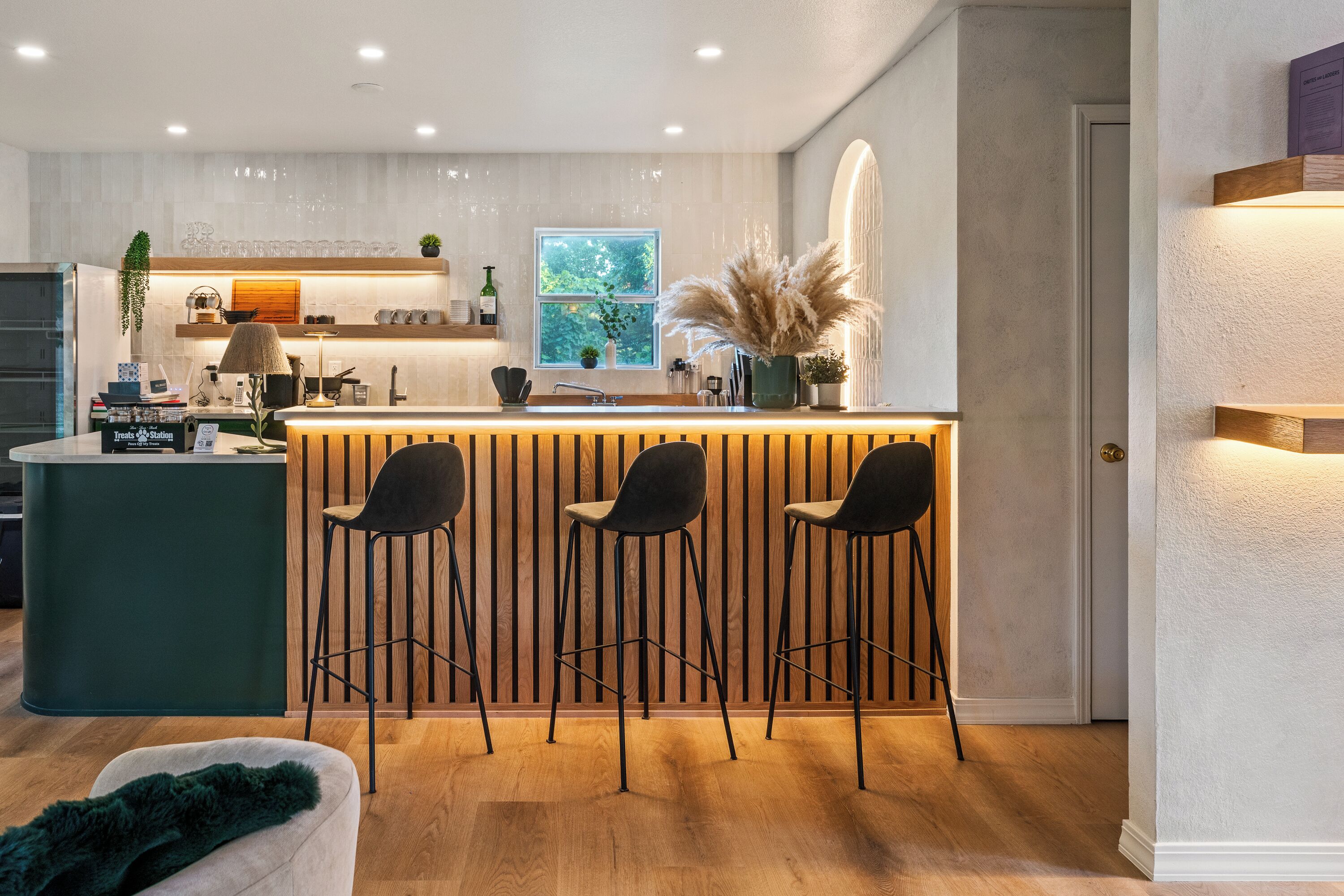 A modern kitchen with a bar area, wooden accents, and a view of the outdoors.