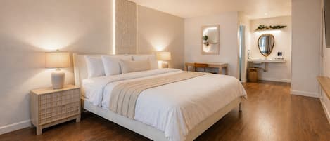 Een slaapkamer met een bed, nachtkastjes, een spiegel, een klein tafeltje en een plank met een plant.