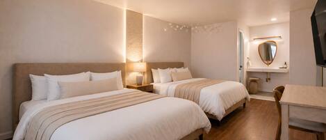 A hotel room with two beds, a small table, a chair, a TV, and a mirror on the wall.