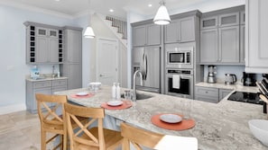 A modern kitchen with grey cabinets, stainless steel appliances, and a marble countertop. - **THE SOPHISTICATED SANDPIPER** Home & Pool + Last Key White Glove Service... (Key West)