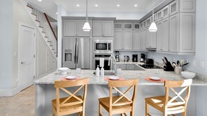 A modern kitchen with grey cabinets, stainless steel appliances, and a central island with bar stools. - **THE SOPHISTICATED SANDPIPER** Home & Pool + Last Key White Glove Service... (Key West)
