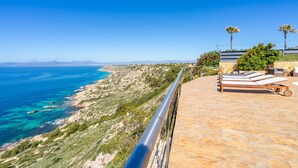 A coastal property with a terrace, lounge chairs, and a view of the sea. - Sa Torre Voramar - with private swimming pool (LLucmajor)