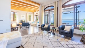 A spacious living room with a large glass coffee table, two sofas, and a view of the sea. - Sa Torre Voramar - with private swimming pool (LLucmajor)