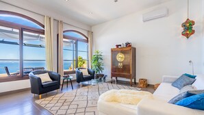 A spacious living room with a large window, a sofa, a coffee table, and a cabinet. - Sa Torre Voramar - with private swimming pool (LLucmajor)