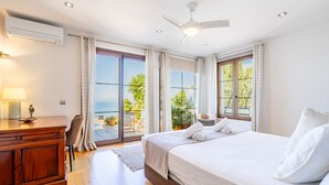 A bedroom with a bed, a desk, a chair, a ceiling fan, and a view of the outdoors. - Sa Torre Voramar - with private swimming pool (LLucmajor)