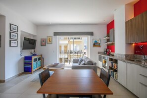 A modern kitchen with a dining area, a TV, and a view to the outside. - Pool, Gym & Balcony | Perfect Romantic Zone Stay (Puerto Vallarta)