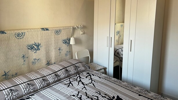 Una camera da letto con un letto, un armadio e una lampada fissata al muro.