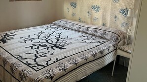 Una camera da letto con un letto, una finestra, una testiera e una sedia.