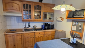 Eine Küche mit Holzausstattung, Spüle, Kaffeemaschine und Mikrowelle.