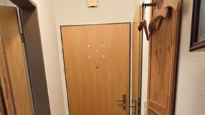 Ein Flur mit Holztür, Fußmatte und Holzschrank.