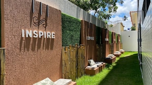 Un área de spa con una pared texturizada, un cartel que dice 'INSPIR' y una fila de bancos de madera con cojines.