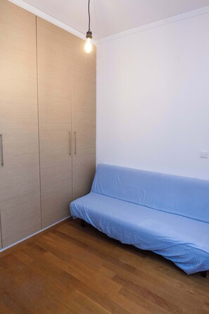 Une pièce avec une armoire en bois, un canapé bleu et une ampoule suspendue au plafond.