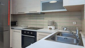 A modern kitchen with stainless steel appliances, a microwave, oven, and a sink. - Bright Minimal 2 Bd Apt in Marousi (Marousi)