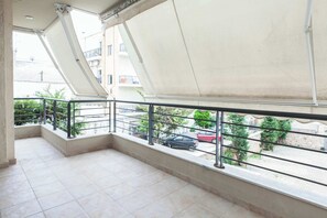 Un balcon donnant sur une rue, avec des balustrades et un sol carrelé.