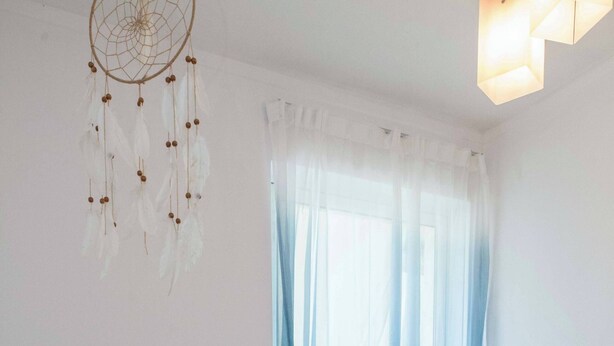 A bedroom with a large bed, white bedding, a dreamcatcher, and a radiator. - Bright Minimal 2 Bd Apt in Marousi (Marousi)