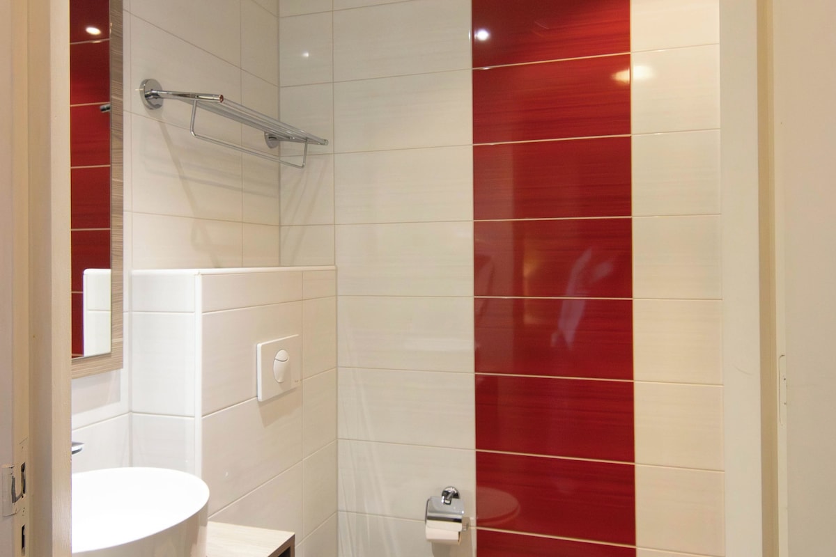 Une salle de bain avec un lavabo blanc, des toilettes et un mur d’accent rouge.