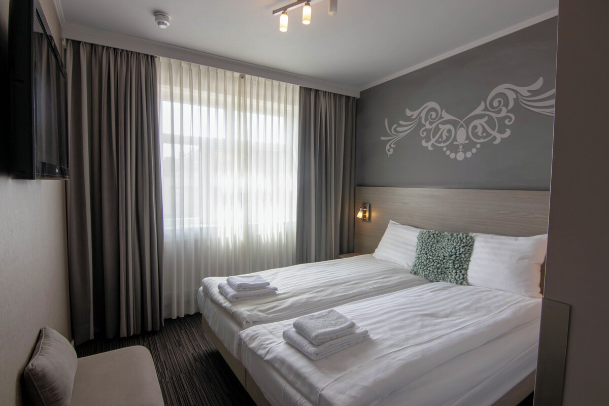 Una habitación de hotel con una cama grande, un televisor y una ventana con cortinas.