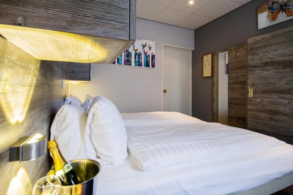 Ein Hotelzimmer mit einem Bett, einer Champagnerflasche und einer Wandleuchte.