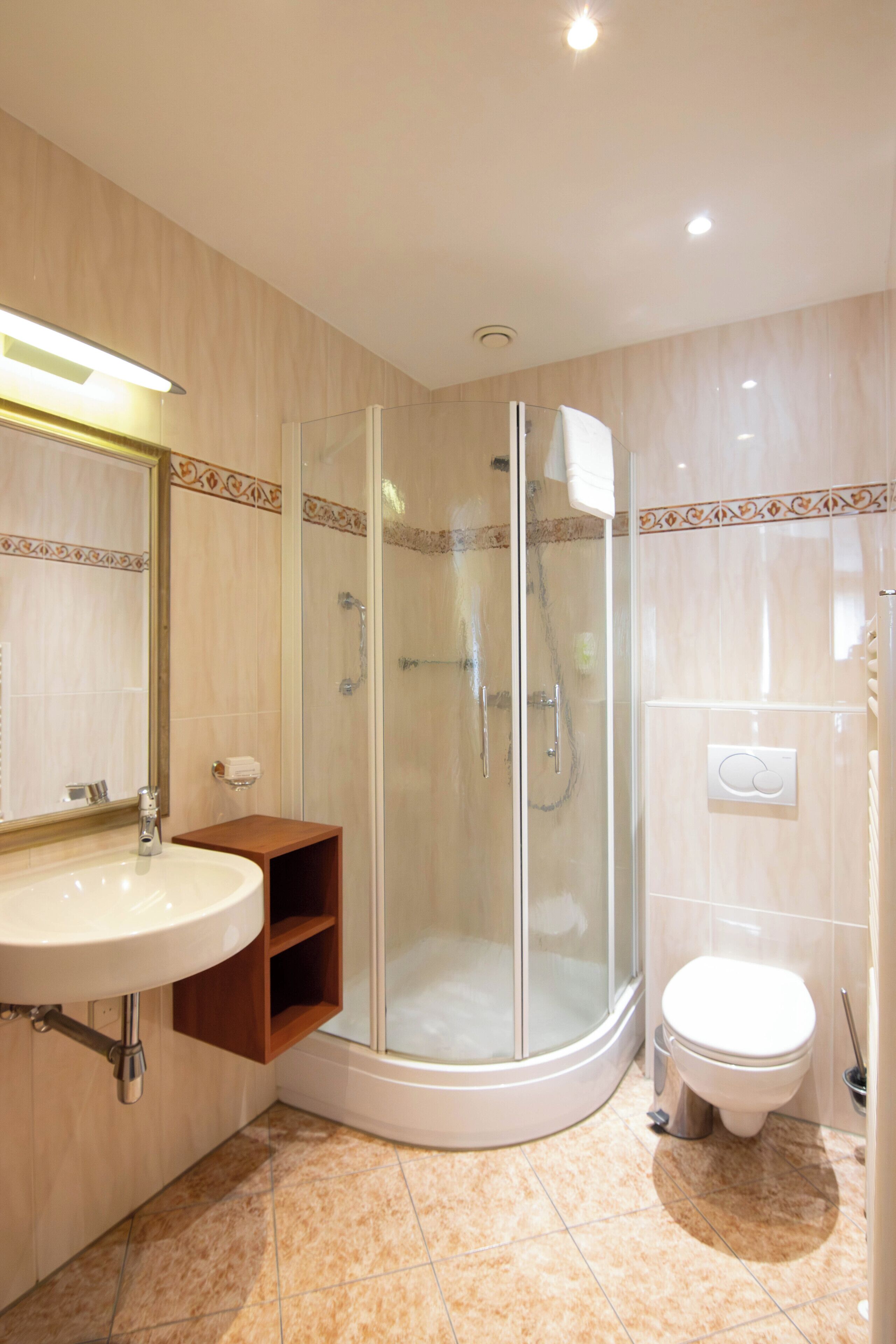 A bathroom with a glass-enclosed shower, a sink with a mirror, and a toilet.