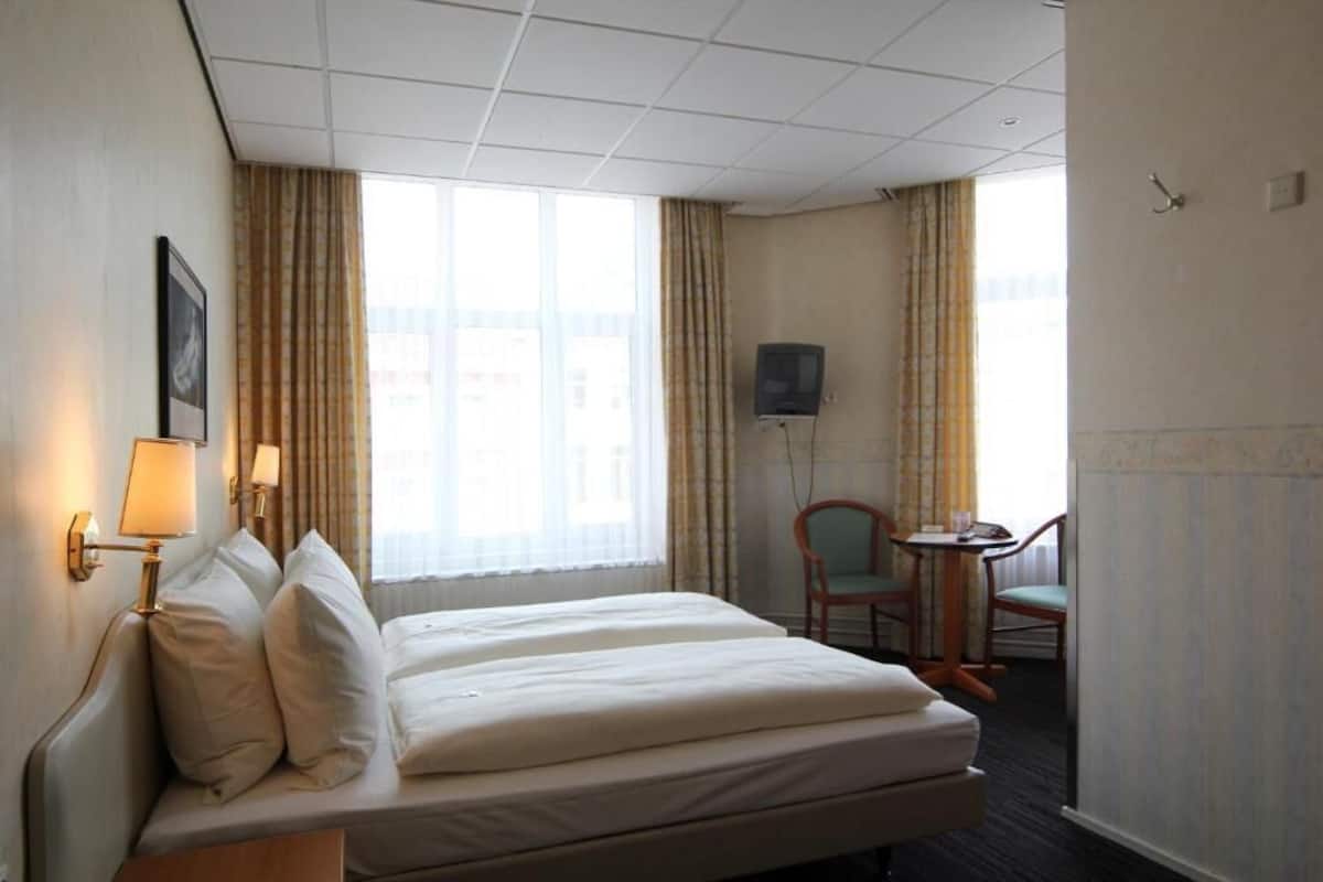 Habitación de hotel con cama, escritorio, silla y televisor.