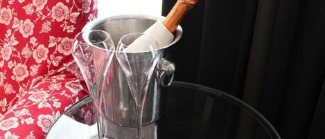 A champagne bottle in a metal bucket with glasses.