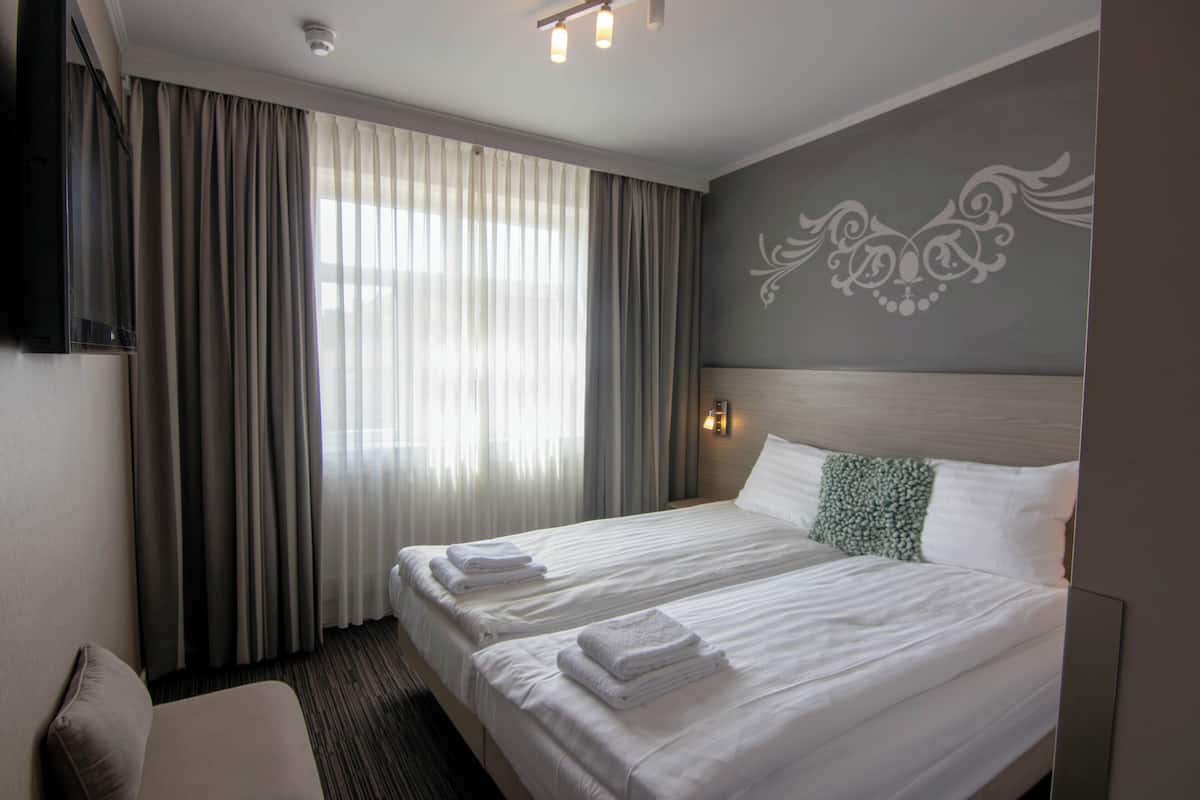 Una habitación de hotel con una cama grande, un televisor y una ventana con cortinas.