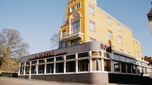 Un hotel con una construcción en esquina, ventanas amplias y un letrero que dice 'HOTEL MONOPOLI'.