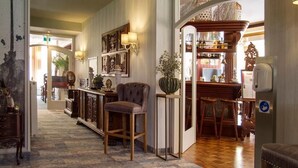 Un vestíbulo de hotel con una zona de bar, un área de descanso con una silla y un letrero en el suelo.