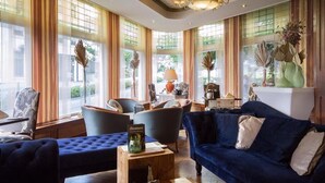 Una habitación bien iluminada con un sofá azul, sillones y un comedor.