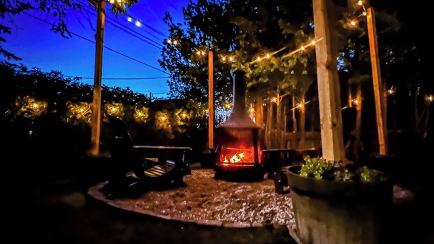 A patio area with a wood-burning stove, string lights, and a potted plant. - Beautiful cottage located just steps from the main beach (Sauble Beach)