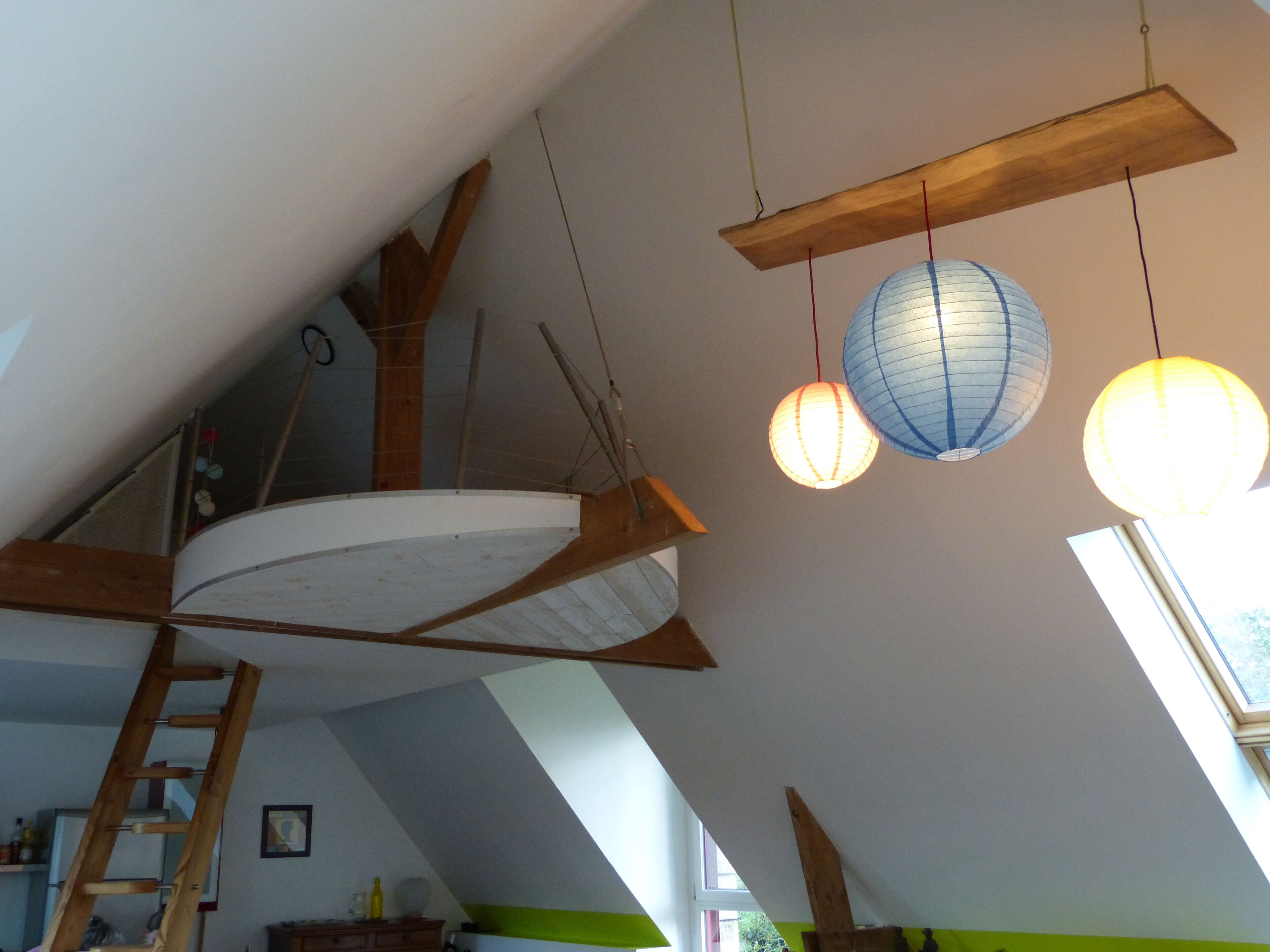 Une pièce de style « loft » avec un plafond en pente, des poutres en bois et une lucarne.