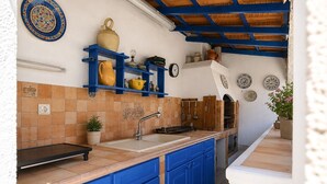 Une cuisine avec des meubles bleus, un évier et des assiettes décoratives accrochées au mur.