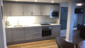 A modern kitchen with grey cabinets, a built-in oven, a microwave, and a sink. - New beach front sea view apartment superking or twin. Featured in Netflix series (Deal)