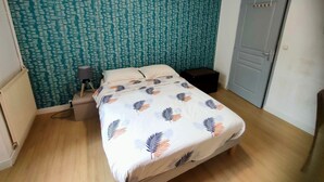 Une chambre à coucher comprenant un lit, une table de chevet, une lampe, une armoire et un mur décoré d’un motif.